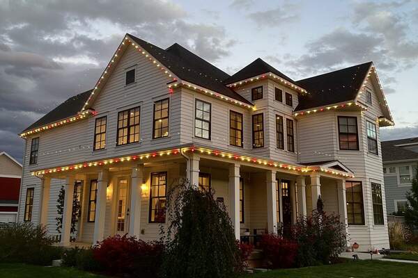 Red and white candy cane Christmas lights on a white two-story home in Utah County, installed by Christmas Light Co.
