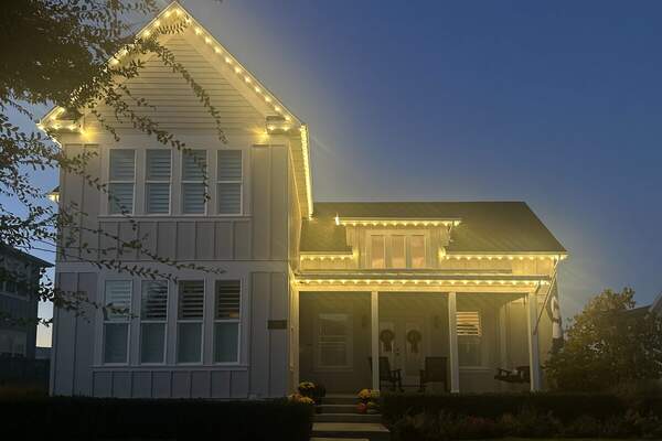 Christmas lights on a farmhouse-style home at dusk in Utah County