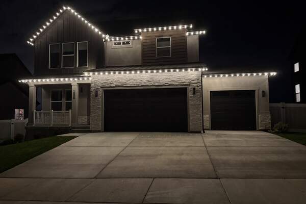 Warm white Christmas lights on a modern two-story home in Utah County